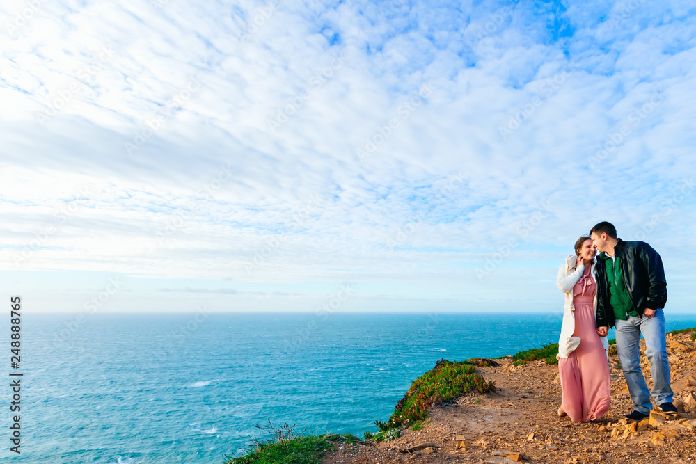 a couple in love hold hands on the high ocean shore.