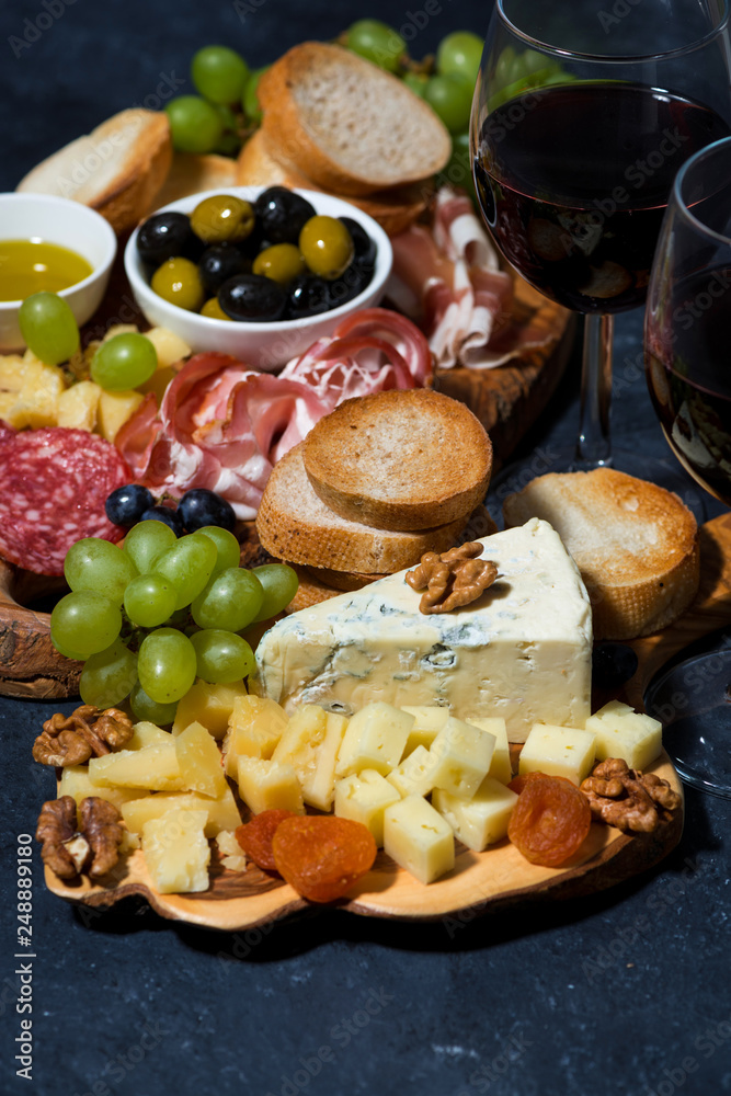 cheese platter on a wooden board, bread, fruit and cold cuts, vertical cheese platter on a wooden board, bread, fruit and cold cuts, vertical