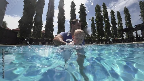 Happy smiling toddler is diving under water with father