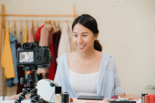 Beauty blogger present beauty cosmetics sitting in front camera for recording video. Beautiful asian woman use cosmetics review make up tutorial broadcast live video to social network by internet.