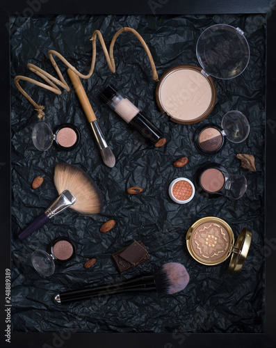 painting of make up brushes  with cosmetics and nature chocolate on black background