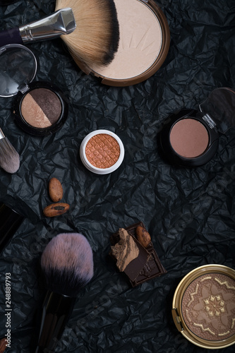 set of cosmetics and nature chocolate on black background