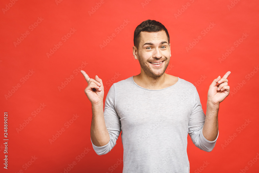 Happy smiling young man presenting and showing your text or product isolated on red background.