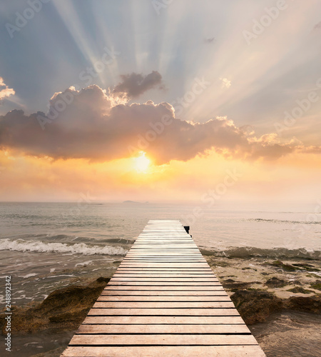 Wood bridge on the sea which has walk way for travel with beautiful sky and sunshine background.