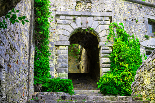 Stone walls  arches  stairs  lamp and green dangling plants of ancient Castello Doria castle tower in Portovenere town  La Spezia  Liguria  Italy