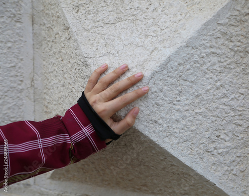 hand of a child on the wall made with stones in the shape of a t