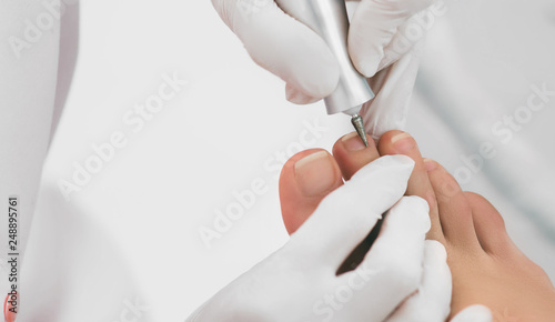 Chiropodist removes the cuticle on the nails using hardware. Chiropodist service