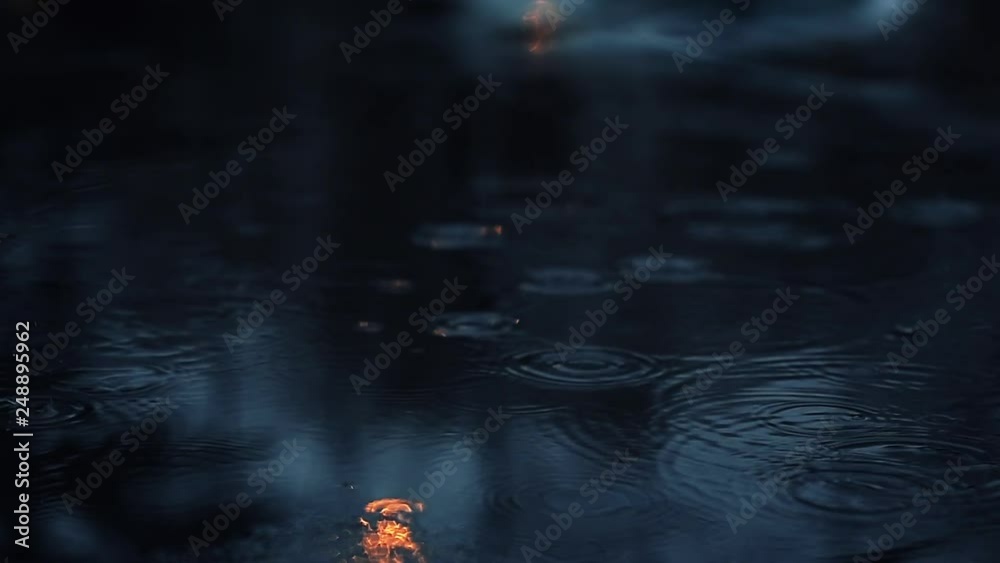 Drizzle raindrop ripples in a pond at night in slow motion