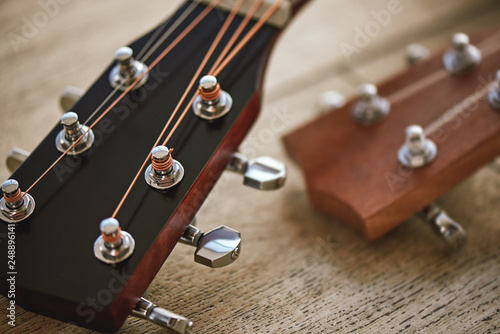 Sound adjusting. Close up photo of guitar necks with tuning keys for adjusting strings against wooden background.