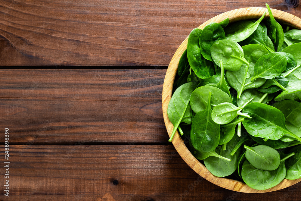 Fresh spinach leaves on wooden background. Healthy vegan food. Top view. Fresh spinach leaves on wooden background. Healthy vegan food. Top view.