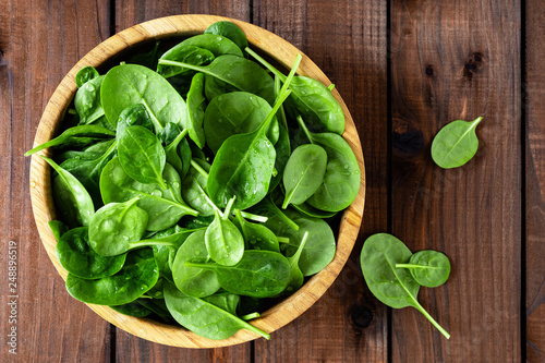 Fresh spinach leaves on wooden background. Healthy vegan food. Top view.