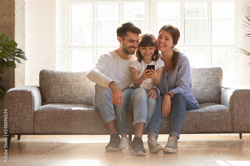 Happy family and kid having fun with smartphone at home