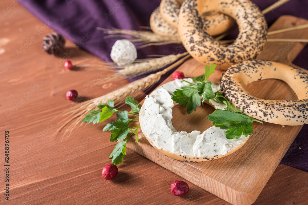Fototapeta premium Whole grain bagels with cream cheese on wooden board