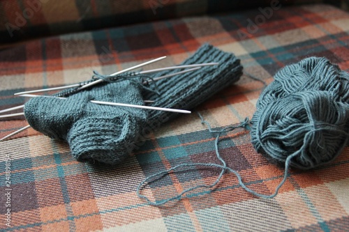 Handmade woolen socks being knit for christmas as a present. Warm and soft blue material with knitting needles and a ball of wool. Often a hobby of grandmothers for the cold winter with spare time 