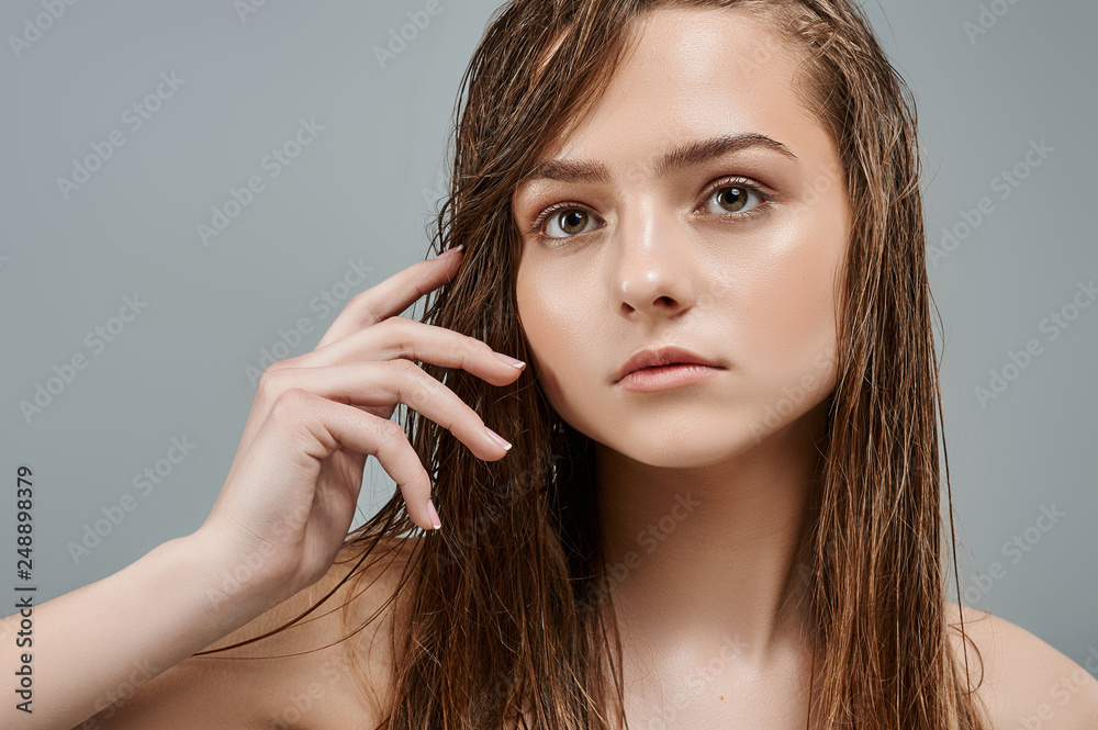 Beautiful young woman with wet make up. Beauty Spa woman with perfect skin portrait. Gestures for advertisement. Gray background Beautiful young woman with wet make up. Beauty Spa woman with perfect skin portrait. Gestures for advertisement. Gray background