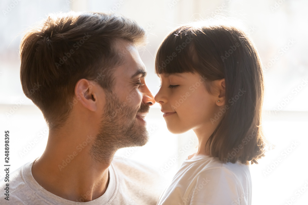 Happy loving father and kid daughter touching noses enjoy tenderness Happy loving father and kid daughter touching noses enjoy tenderness