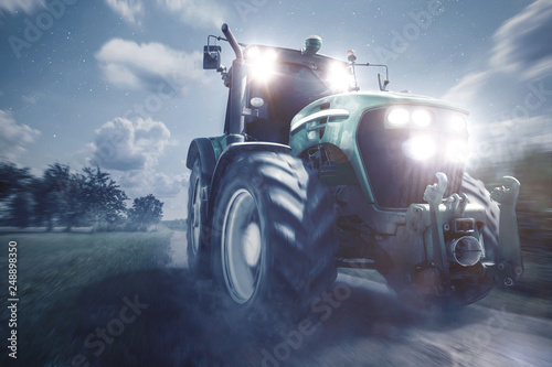 Traktor fährt auf einem Feldweg bei Nacht