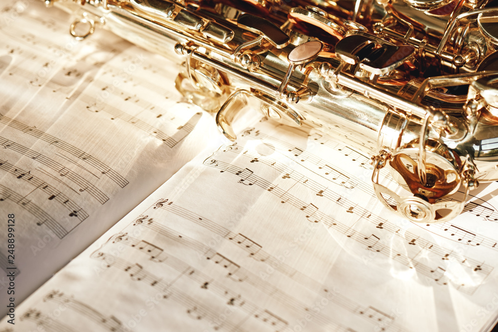 Obraz premium Time for jazz. Close up image of a shiny keys of golden saxophone lying on the sheet of music