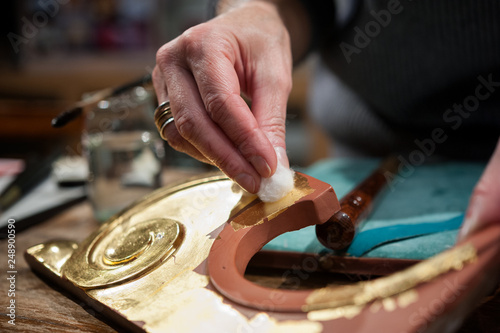 Craftsman uses a cotton pad during the gilding process tecnique.