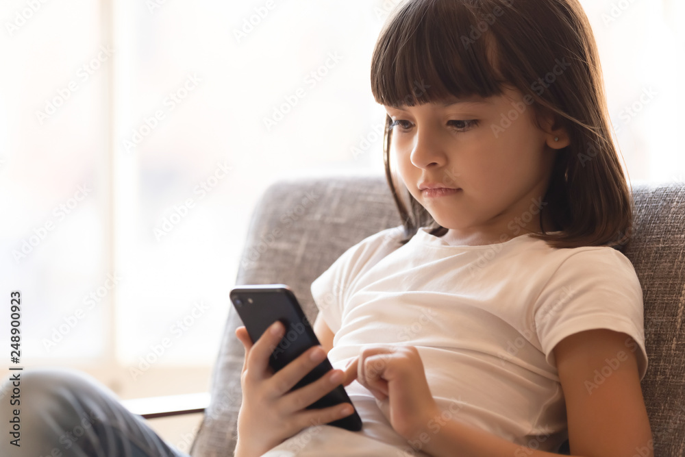 Little smart kid holding smartphone playing game online at home Little smart kid holding smartphone playing game online at home