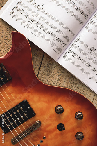 Electric Guitar Chords. Close-up photo of electric guitar body with volume and tone control knobs with music notes against of wooden background.