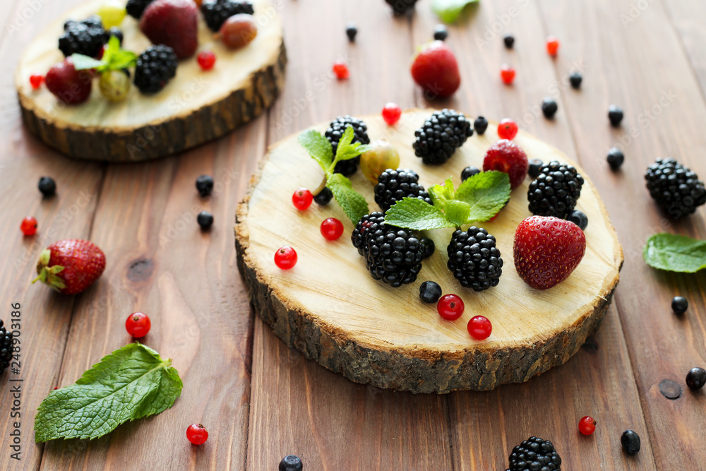 Mix of fresh berries on wooden background. Composition of currant, strawberry, blueberries, gooseberries, blackberries and mint. Mix of fresh berries on wooden background. Composition of currant, strawberry, blueberries, gooseberries, blackberries and mint.