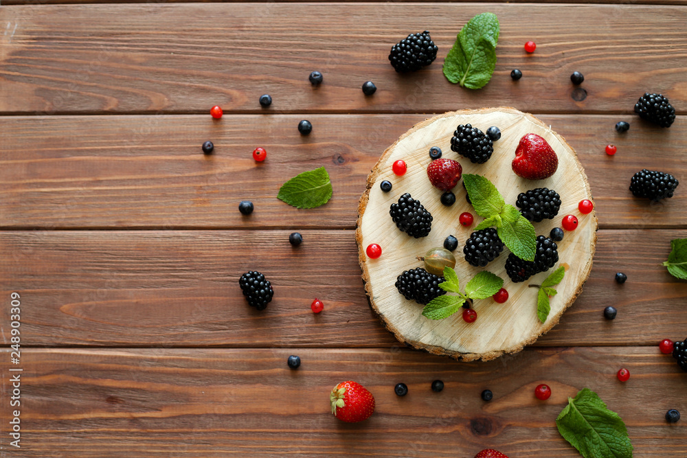 Mix of fresh berries on wooden background. Composition of currant, strawberry, blueberries, gooseberries, blackberries and mint with space for text. Top view. Mix of fresh berries on wooden background. Composition of currant, strawberry, blueberries, gooseberries, blackberries and mint with space for text. Top view.
