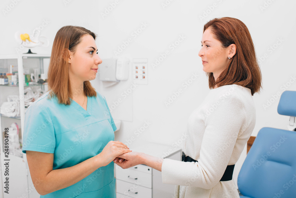 Fototapeta premium Doctor holding a patients hand in comfort and smiling. Medical care and support