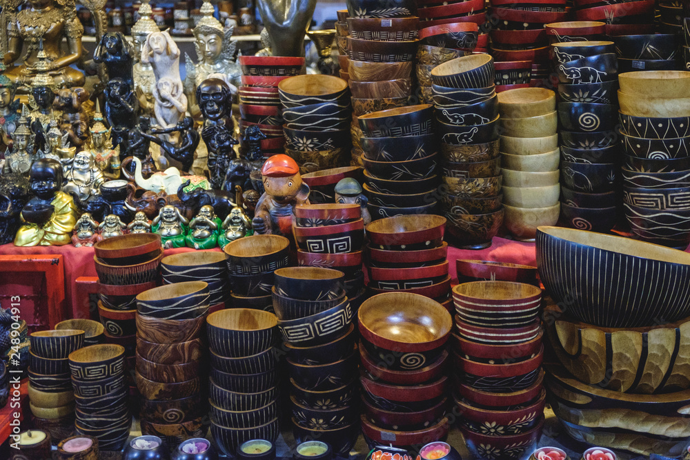 Different hand made bowls and various statues of the gods of luck, a fine souvenirs selling on a local Bang Niang Night Market in Khao Lak, Thailand.