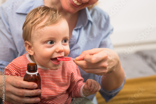 mother giving cough syrup to her little boy