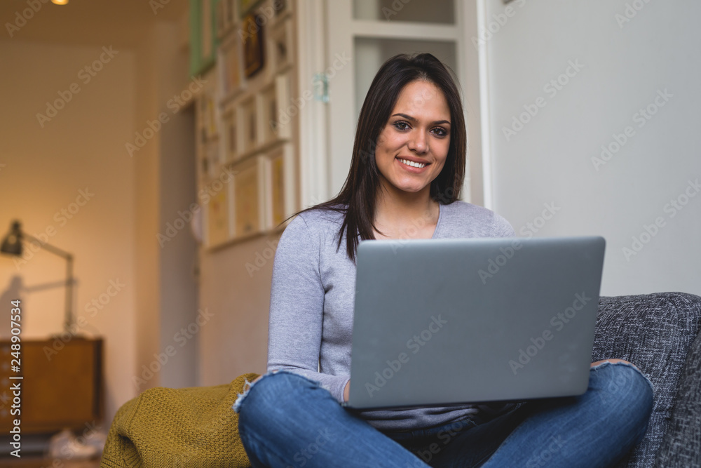 young woman using laptop relaxed on sofa at her home young woman using laptop relaxed on sofa at her home