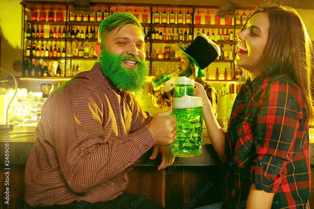 Saint Patrick's Day Party. Happy friends are celebrating and drinking green beer. Young men and women wearing green hats. Pub Interior. Saint Patrick's Day Party. Happy friends are celebrating and drinking green beer. Young men and women wearing green hats. Pub Interior.