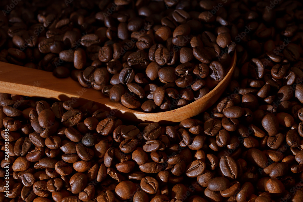 Fototapeta premium A pile of roasted coffee beans with a wooden ladle