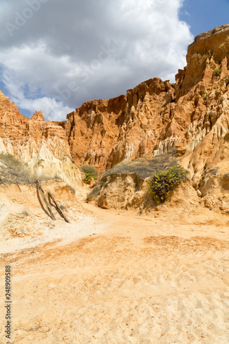 High cliffs along Falesia Beach and The Atlantic Ocean in Albufeira, Algarve, Portugal. Sunny summer day, blue sky with stormy clouds.