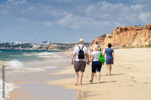 Senior couple walking on the beach in the summer sunny day photo