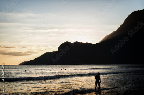 Golden sunset on the beach with a men silhouette and mountain background