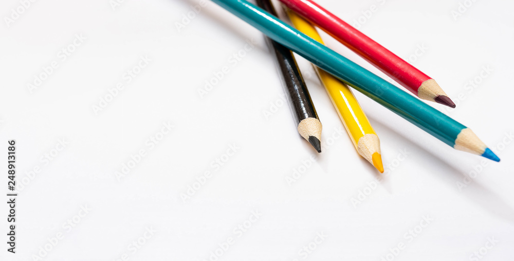 Fototapeta premium Four colored pencils. The colors cyan, magenta, yellow and black. The concept of polygraphy.