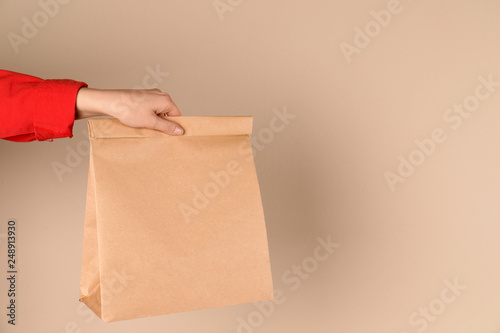 Woman holding paper bag on color background. Mockup for design
