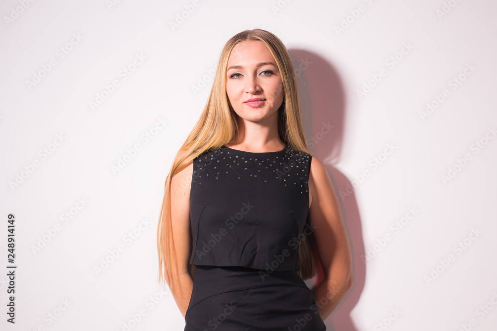 People and fashion concept - Sexy beautiful blond lady model in black dress standing on white background People and fashion concept - Sexy beautiful blond lady model in black dress standing on white background