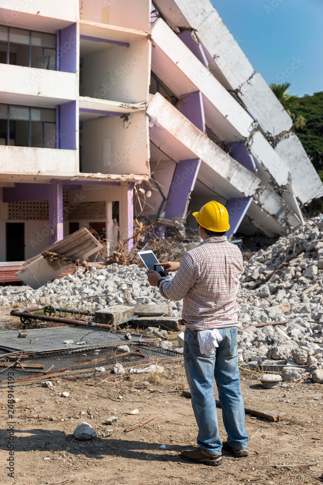 Engineer holding tablet is checking for destruction, demolishing building. Engineer holding tablet is checking for destruction, demolishing building.