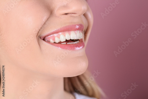 Young woman with healthy teeth and beautiful smile on color background, closeup. Space for text