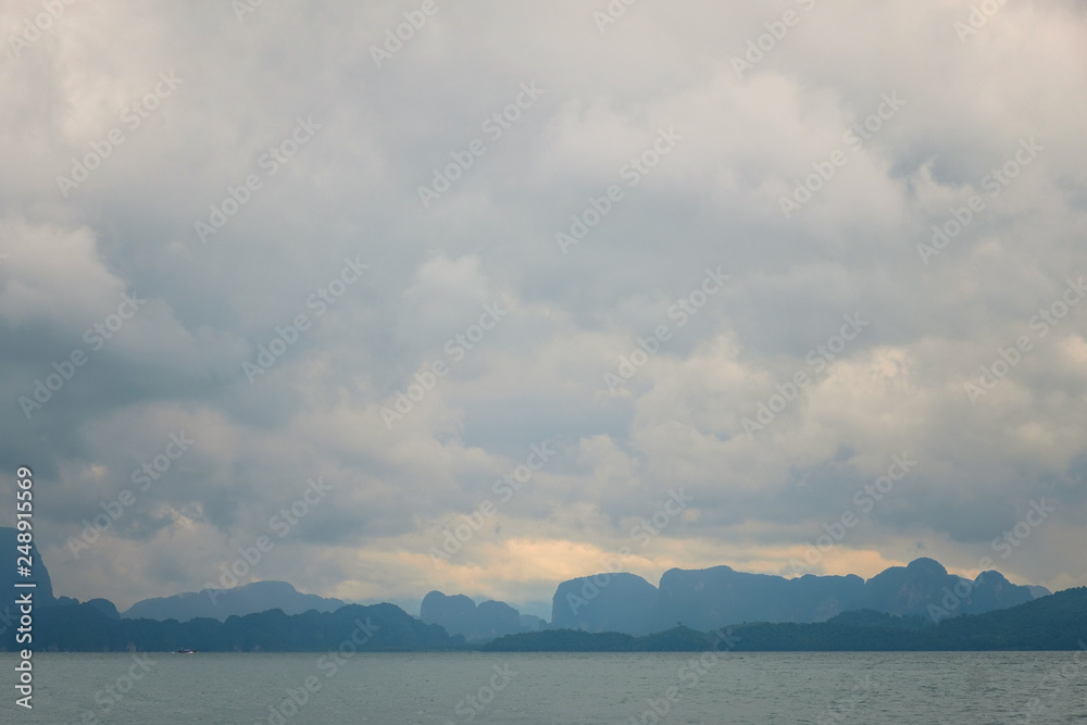 Seascape with a cloudy sky and a rocky coastline on the horizon