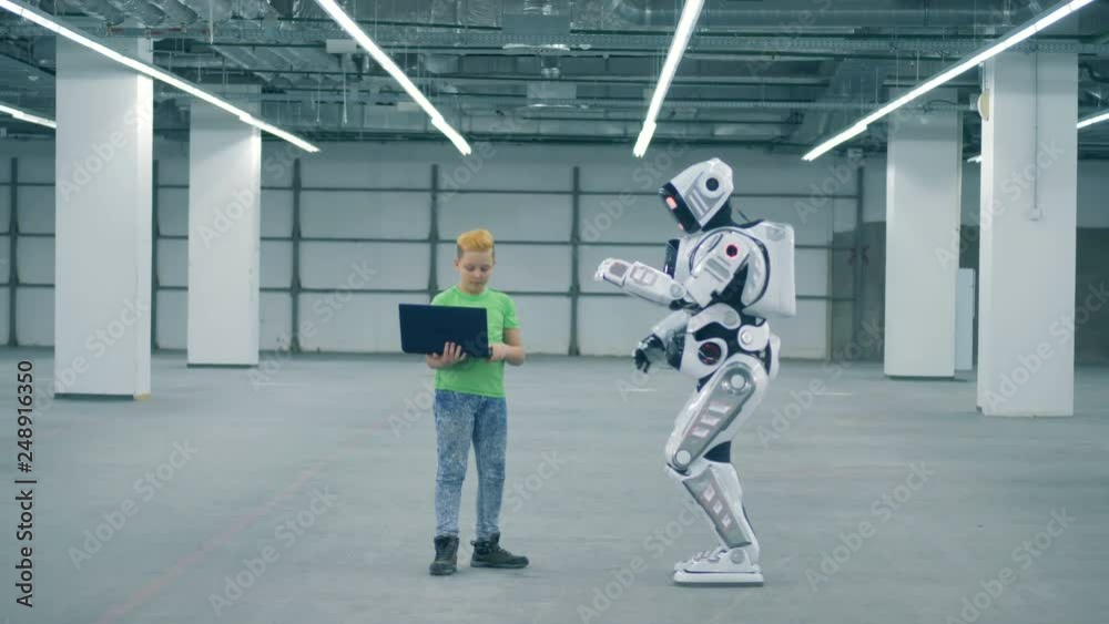 Teenage boy is manipulating a robot to move and turn around Teenage boy is manipulating a robot to move and turn around