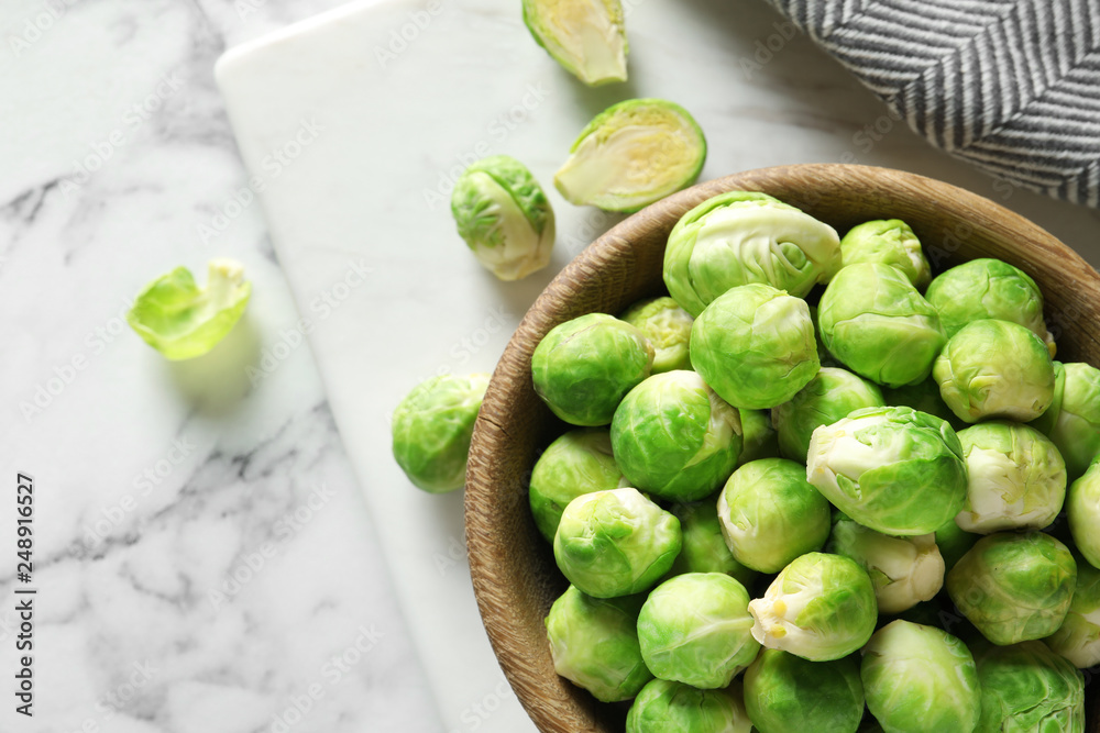 Bowl with fresh Brussels sprouts on marble table, top view. Space for text Bowl with fresh Brussels sprouts on marble table, top view. Space for text