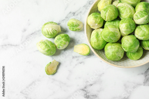 Bowl with fresh Brussels sprouts on marble table, top view. Space for text