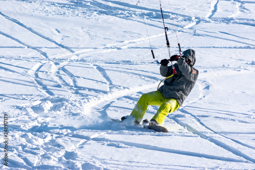Snowboarder on a snowboard with snow kite on the fresh snow. Concept of outdoor extreme activities in winter snowkite