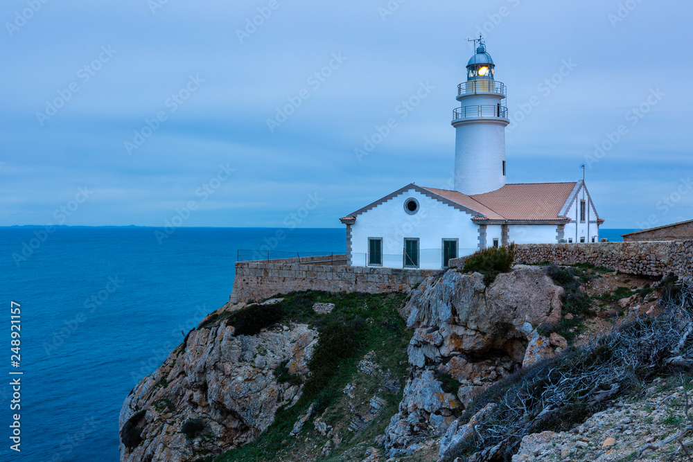 Leuchtturm auf einem Felsen umringt vom Meer, zur blauen Stunde