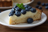 Healthy dessert. Piece of blueberry tart or cake with cream. Fresh sweet dessert with fruits. Top view. Wooden, rustic background.