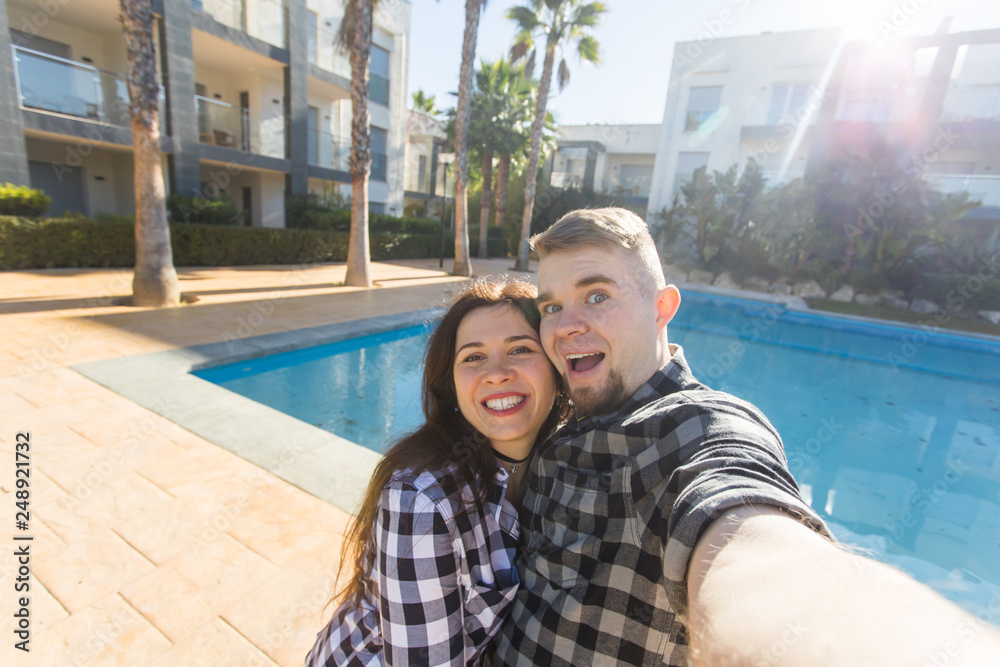 Travel, vacation and holiday concept - Young couple selfie smartphone photo near a swimming pool. Travel, vacation and holiday concept - Young couple selfie smartphone photo near a swimming pool.