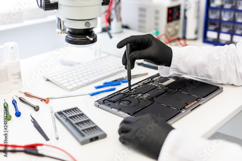Φωτογραφία Engineer with small tool and black gloves repairing motherboard of laptop comput